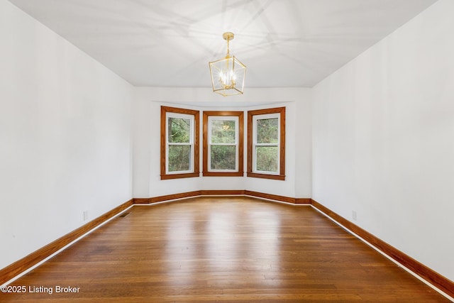 unfurnished room featuring a notable chandelier, visible vents, baseboards, and dark wood-type flooring