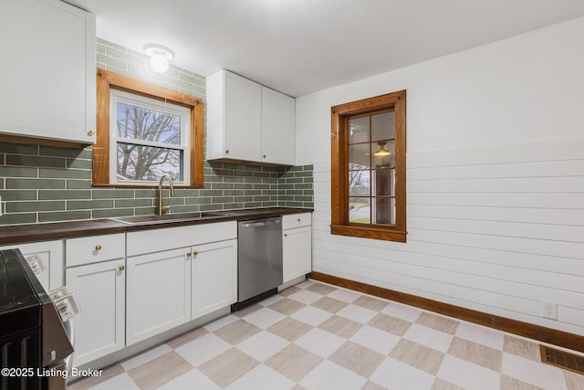 kitchen featuring a sink, white cabinets, dishwasher, light floors, and dark countertops