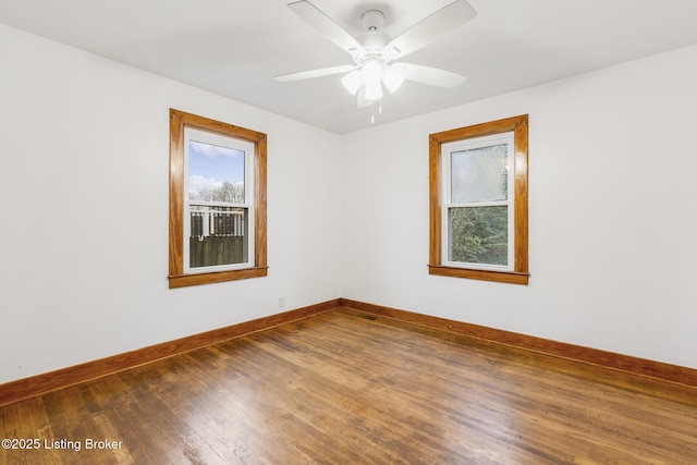 empty room featuring wood finished floors, a ceiling fan, and baseboards