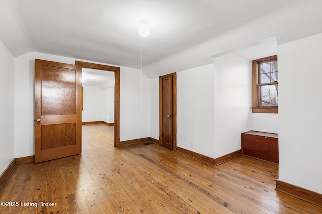 additional living space featuring lofted ceiling, wood-type flooring, and baseboards