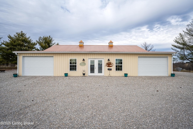 ranch-style house featuring french doors, metal roof, and a detached garage