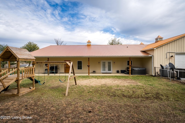 rear view of house featuring french doors, a lawn, a hot tub, a patio area, and metal roof