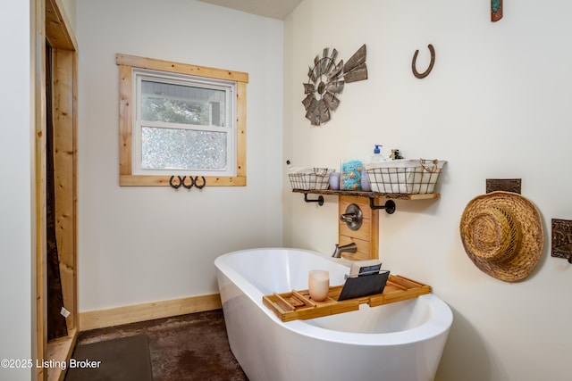 full bath with a freestanding bath and baseboards