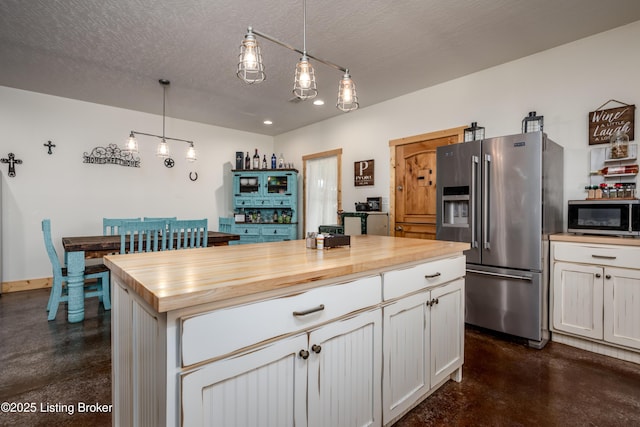 kitchen with finished concrete flooring, butcher block counters, stainless steel appliances, and a textured ceiling