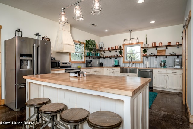 kitchen featuring open shelves, stainless steel appliances, visible vents, a sink, and wood counters