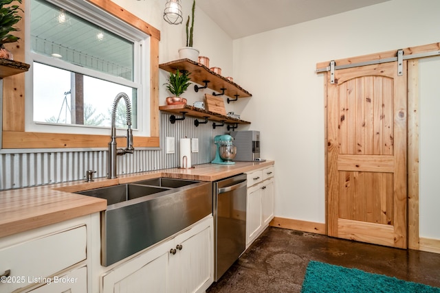 kitchen with open shelves, wooden counters, stainless steel dishwasher, a barn door, and a sink