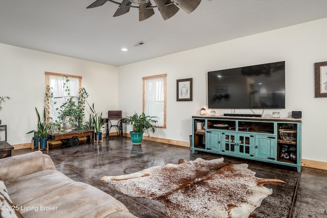 living area featuring a ceiling fan, visible vents, concrete floors, and baseboards