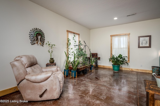 living area with concrete flooring, recessed lighting, visible vents, and baseboards