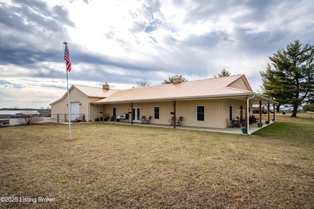 back of house with metal roof, a lawn, and a patio