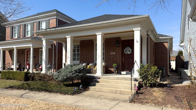 view of front of property with a shingled roof, central AC unit, a porch, and brick siding