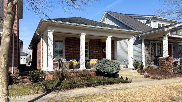 view of front of property with a shingled roof, a porch, and brick siding