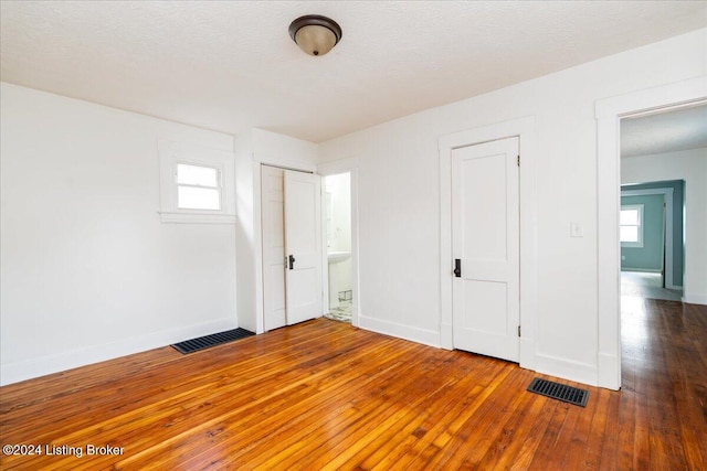 unfurnished bedroom featuring hardwood / wood-style flooring, baseboards, and visible vents