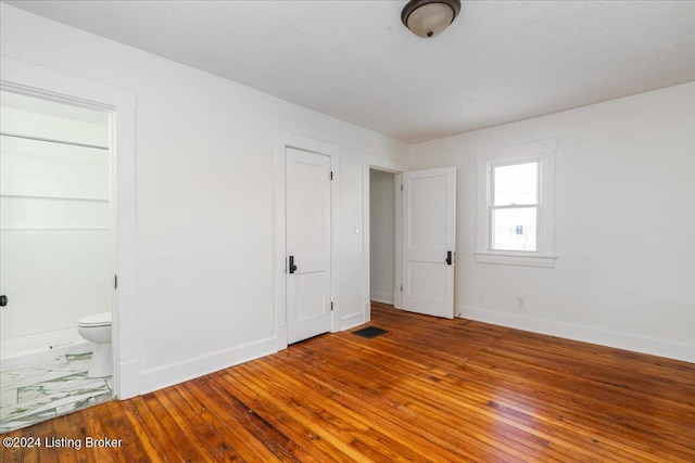 unfurnished bedroom featuring baseboards, visible vents, and hardwood / wood-style floors