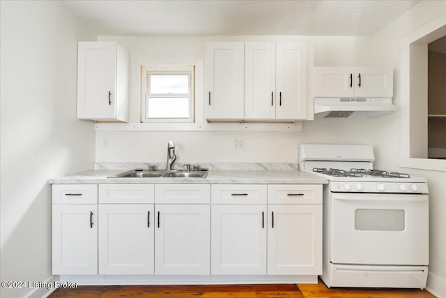 kitchen featuring white cabinets, white gas range, light countertops, under cabinet range hood, and a sink