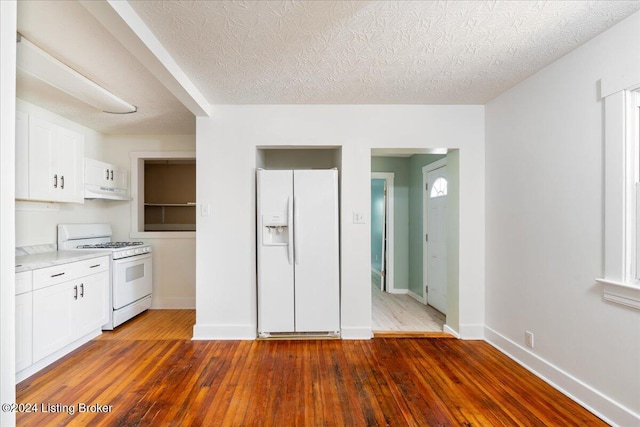 kitchen featuring under cabinet range hood, white appliances, white cabinets, light countertops, and hardwood / wood-style floors