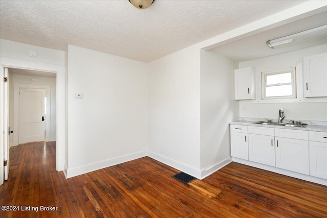 interior space featuring dark wood-style flooring, visible vents, a sink, and baseboards