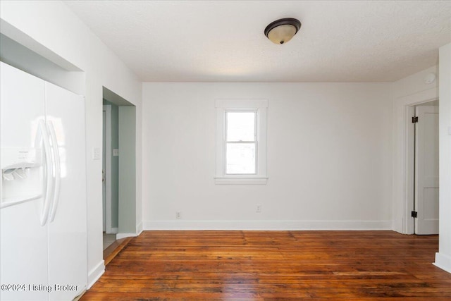 spare room with a textured ceiling, wood finished floors, and baseboards