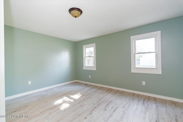 unfurnished room with wood finished floors, visible vents, and baseboards