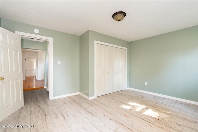 unfurnished bedroom with light wood-style floors, baseboards, and a closet