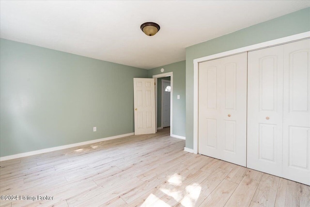 unfurnished bedroom with a closet, light wood-style flooring, and baseboards