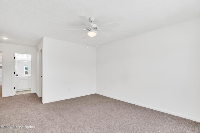 spare room featuring light carpet, baseboards, and a ceiling fan