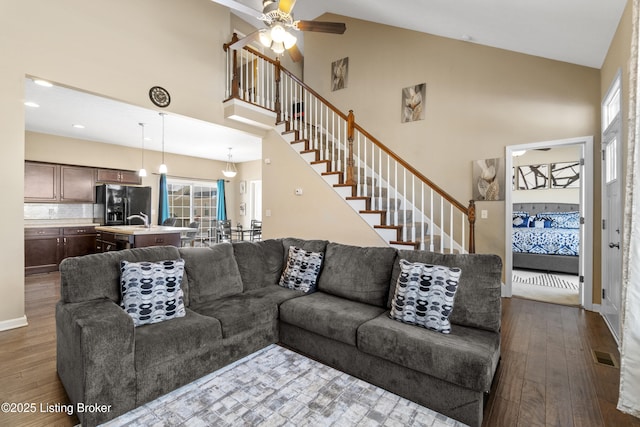 living area with visible vents, plenty of natural light, stairway, and wood finished floors