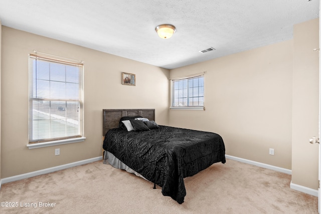 carpeted bedroom with baseboards, visible vents, and a textured ceiling