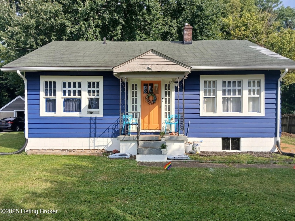 bungalow-style home with a shingled roof, a front yard, and a chimney