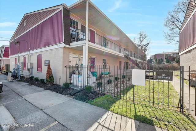 exterior space with brick siding, central AC unit, and fence