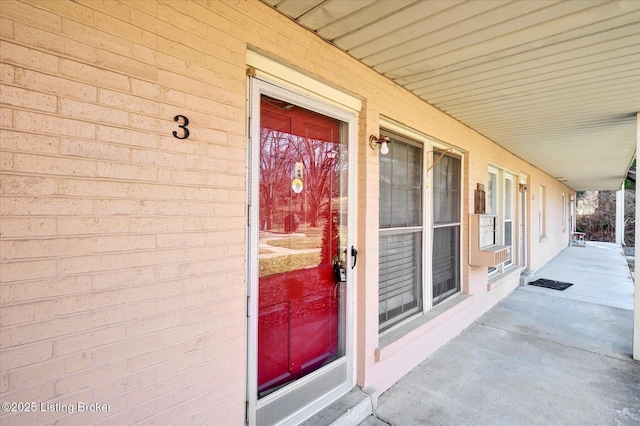 view of exterior entry with brick siding and a porch