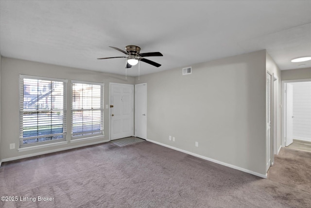 unfurnished room with carpet flooring, baseboards, visible vents, and a ceiling fan