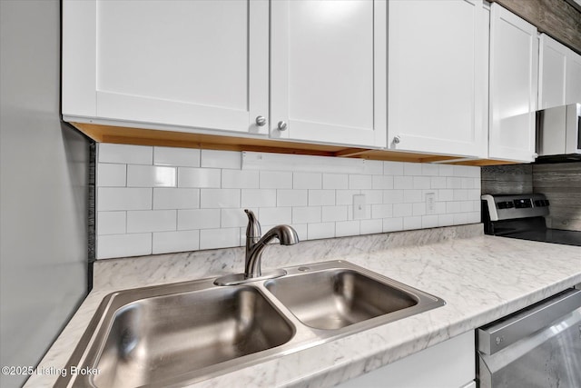 kitchen with a sink, appliances with stainless steel finishes, and white cabinetry