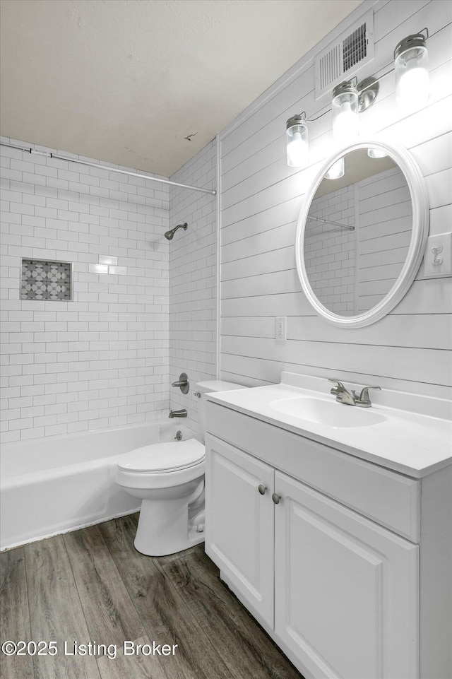 full bathroom with visible vents, toilet, wood finished floors, bathtub / shower combination, and vanity