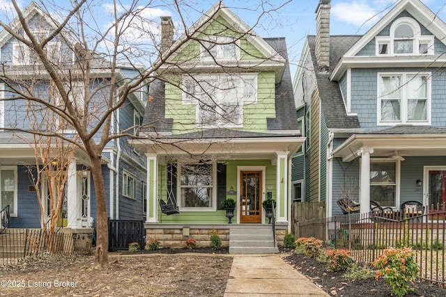 view of front of property featuring roof with shingles, a chimney, and a fenced front yard