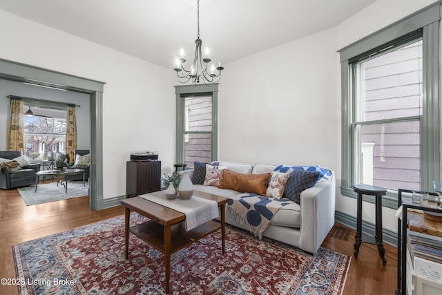 living area featuring a chandelier, baseboards, and wood finished floors