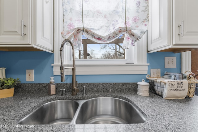 interior details featuring stone counters, white cabinetry, and a sink