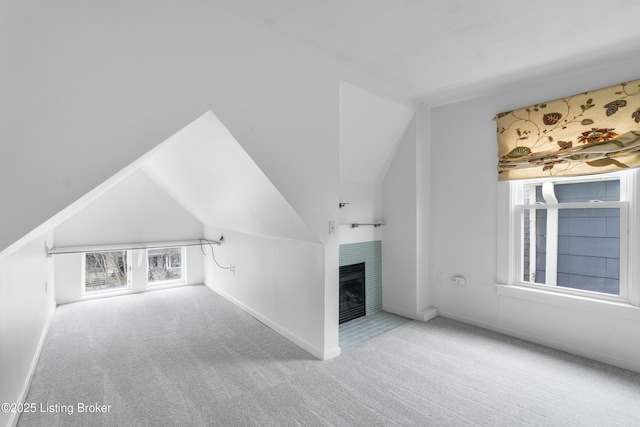 bonus room with baseboards, light colored carpet, vaulted ceiling, and a fireplace