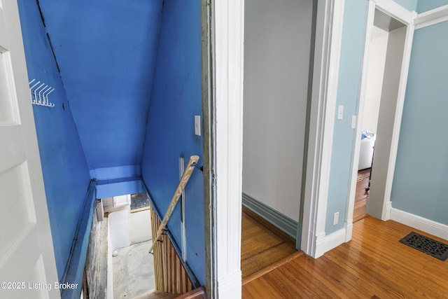 staircase featuring wood finished floors, visible vents, and baseboards