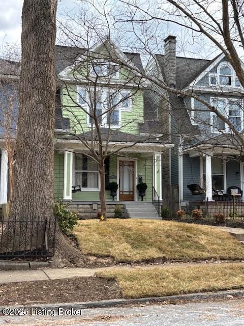 view of front of home featuring a chimney, a porch, and a front yard