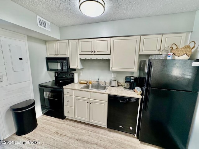 kitchen with visible vents, light wood-style flooring, light countertops, black appliances, and a sink