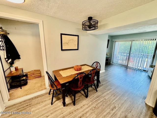 dining area with a textured ceiling, baseboards, and wood finished floors