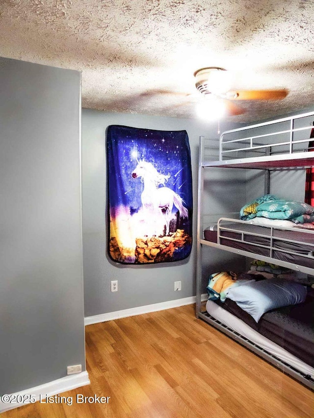 home theater room with a textured ceiling, baseboards, and wood finished floors