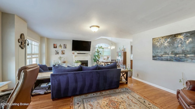 living area featuring light wood-style flooring, a fireplace, and baseboards