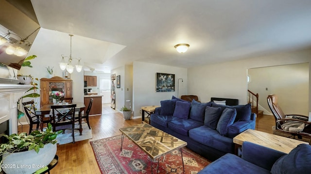 living room with a fireplace, hardwood / wood-style floors, an inviting chandelier, baseboards, and stairs