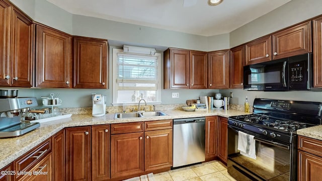 kitchen featuring black appliances, light tile patterned floors, light stone counters, and a sink