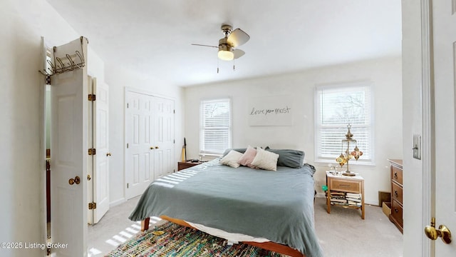 bedroom with light carpet, multiple windows, a ceiling fan, and baseboards