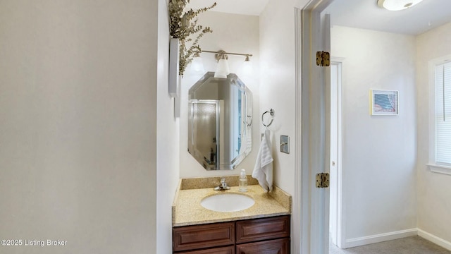 full bath featuring a stall shower, vanity, and baseboards