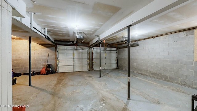 garage featuring concrete block wall and a garage door opener