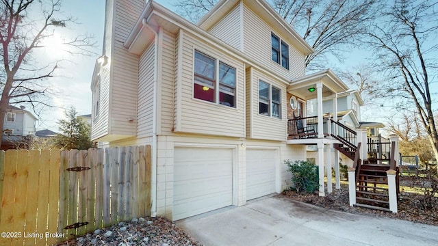 view of property exterior featuring a garage, driveway, stairs, and fence