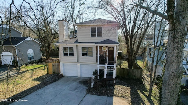 view of front facade with a garage, driveway, a chimney, and fence